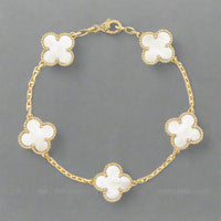 Gold bracelet with white flower-shaped charms on a white background
