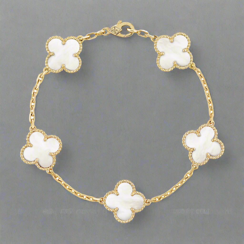 Gold bracelet with white flower-shaped charms on a white background