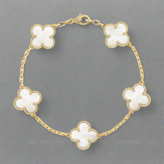 Gold bracelet with white flower-shaped charms on a white background
