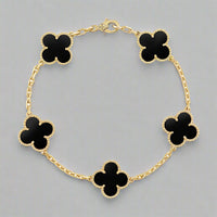Gold bracelet with black clover-shaped charms on a white background