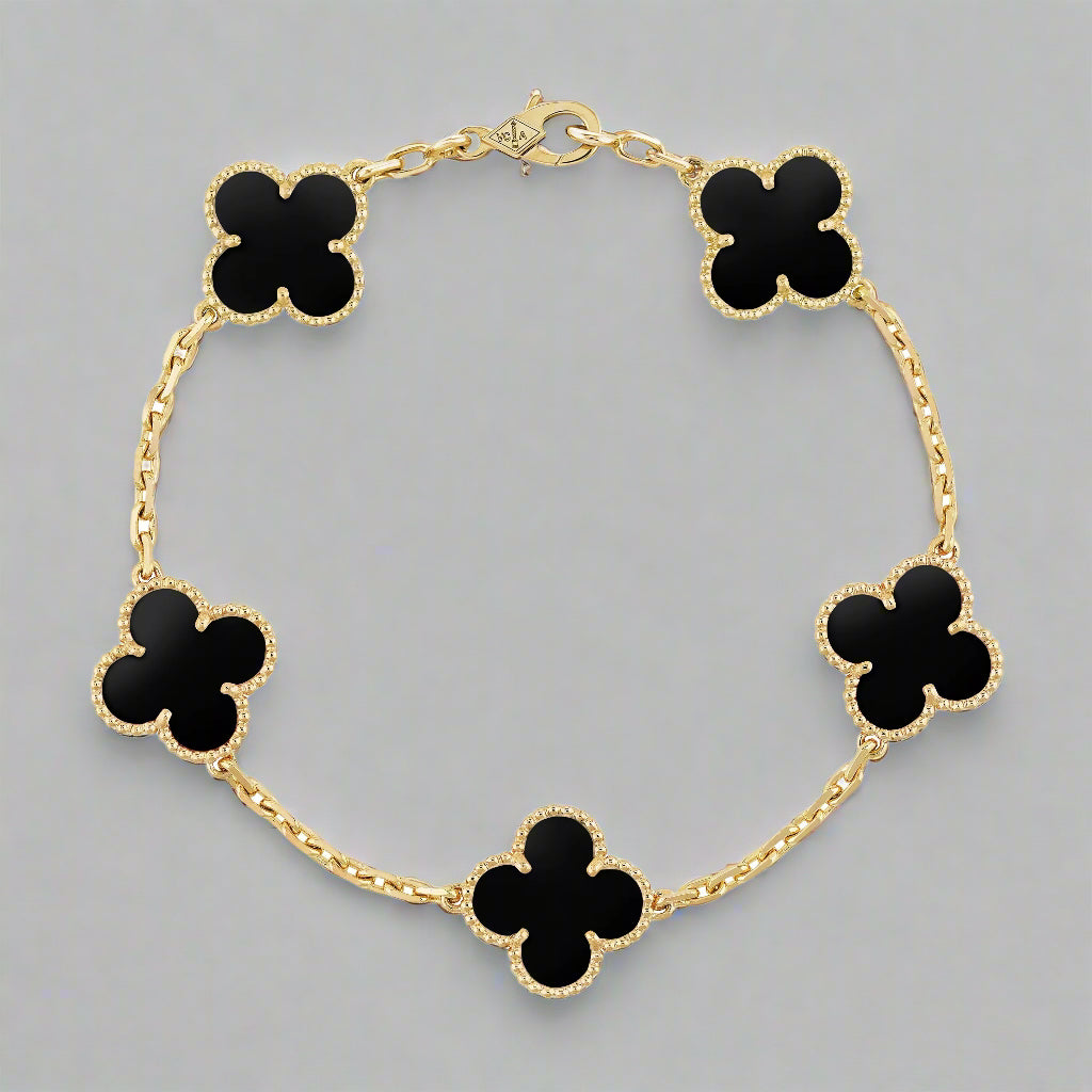 Gold bracelet with black clover-shaped charms on a white background