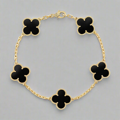 Gold bracelet with black clover-shaped charms on a white background