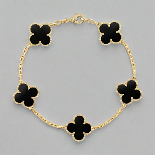 Gold bracelet with black clover-shaped charms on a white background
