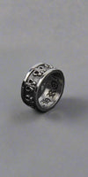 Three silver rings with intricate designs on a dark surface
