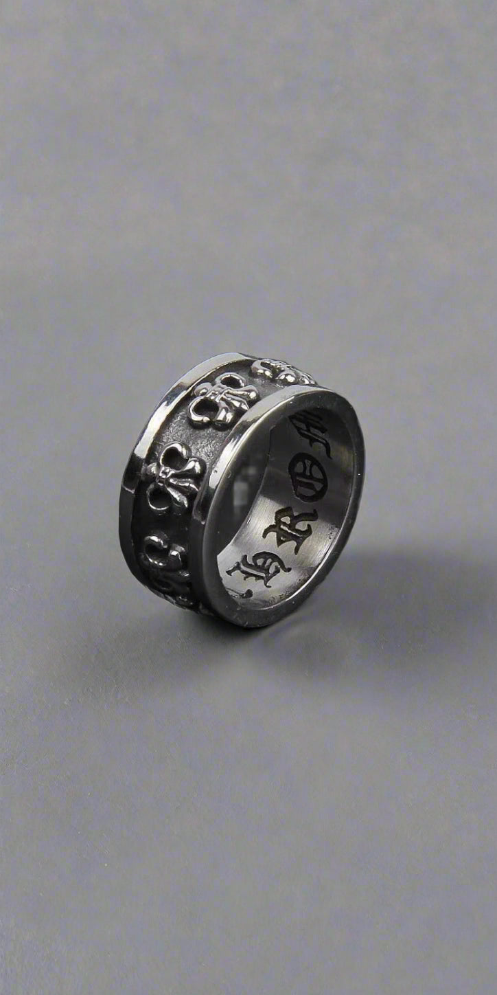 Three silver rings with intricate designs on a dark surface
