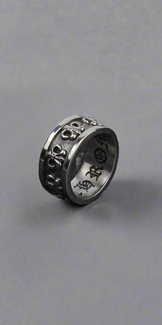 Three silver rings with intricate designs on a dark surface
